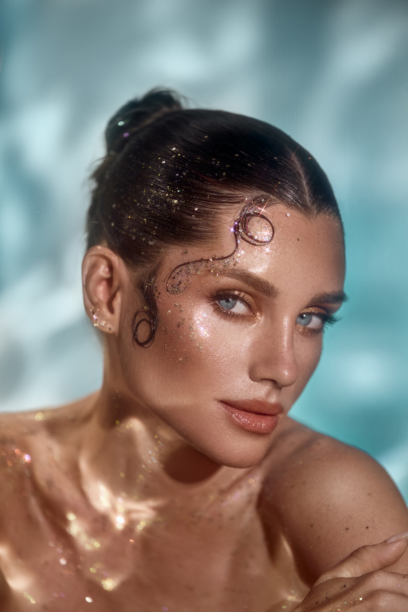 Radiant woman with glowing, shimmering skin in soft aqua light, representing beauty and luxury at Bogat Aesthetics & Wellness.