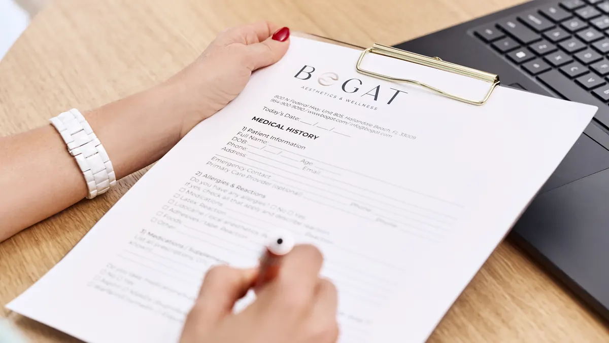 A Bogat medical history intake form on a clipboard being completed before an IV therapy session in Hallandale Beach, FL.